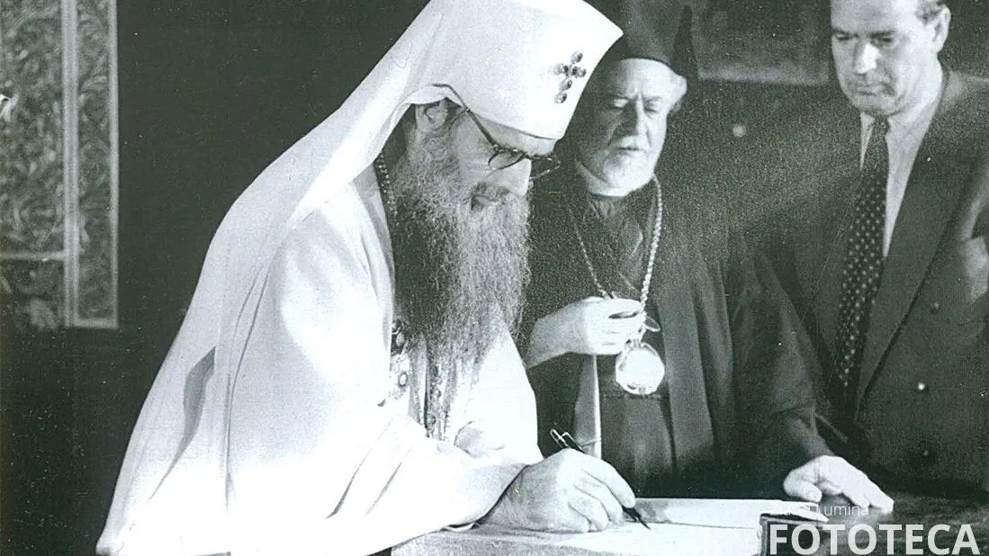 Patriarhul justinian semnand in condica sfanta cu prilejul canonizarii sfintilor romani asistat de profesorul iustin moisescu 1748.jpg