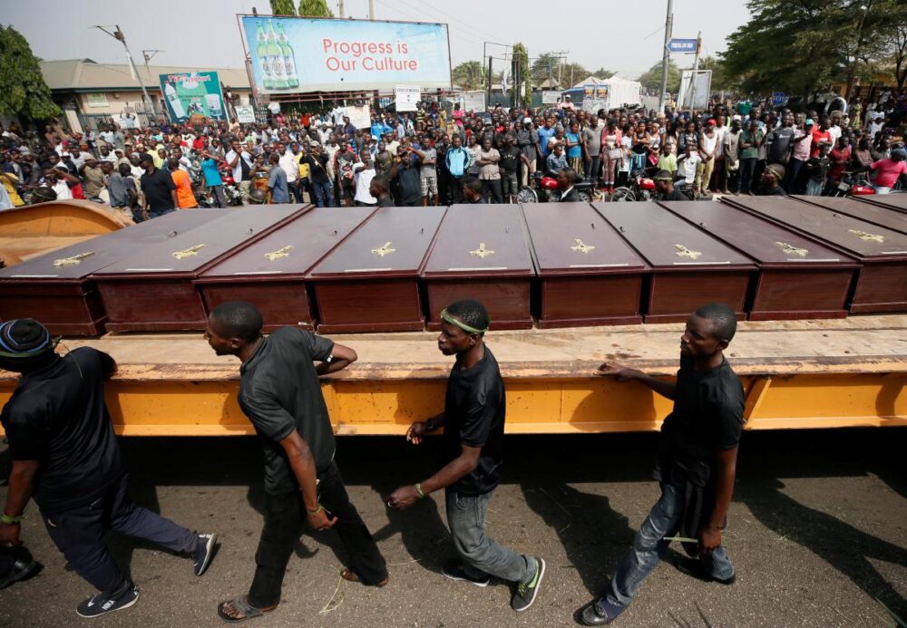 Men march along the truck carrying the coffins of people killed by the Fulani herdsmen, in Makurdi
