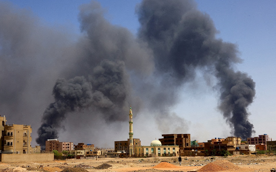 FILE PHOTO: FILE PHOTO: Man walks while smoke rises above buildings after aerial bombardment in Khartoum North