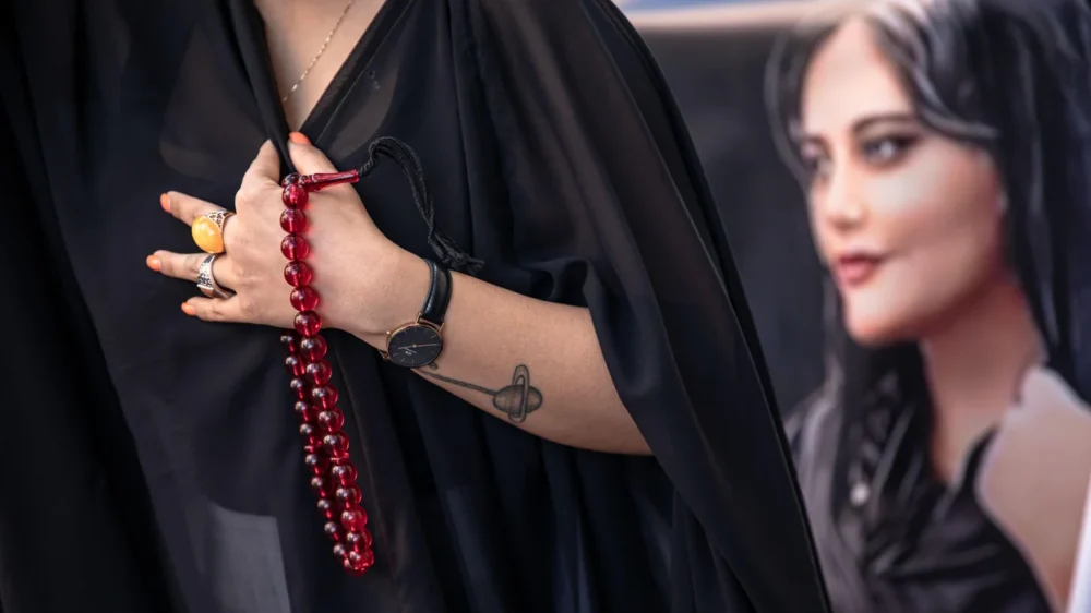 A protester seen holding a rosary and a placard with a picture of mahsa amini during the demonstration in istanbul turkey on n