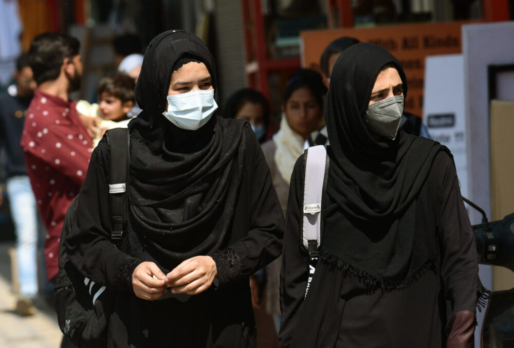 College girls wearing hijab walk near a market on a sunny day