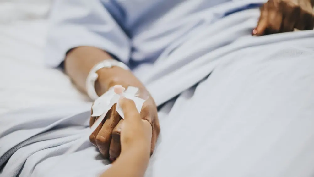 Daughter holding her mothers hand hospital scaled.jpg