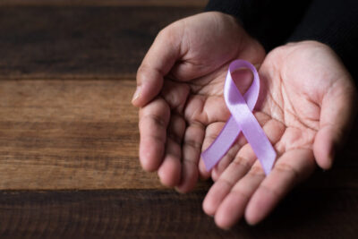 Cropped hands of person holding testicular cancer symbol over wooden table