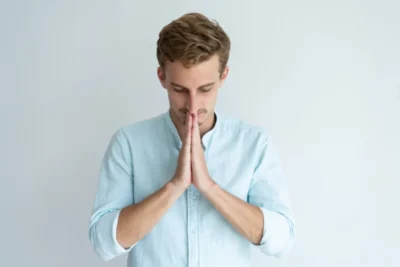 Focused young man praying keeping hands together guy asking god something