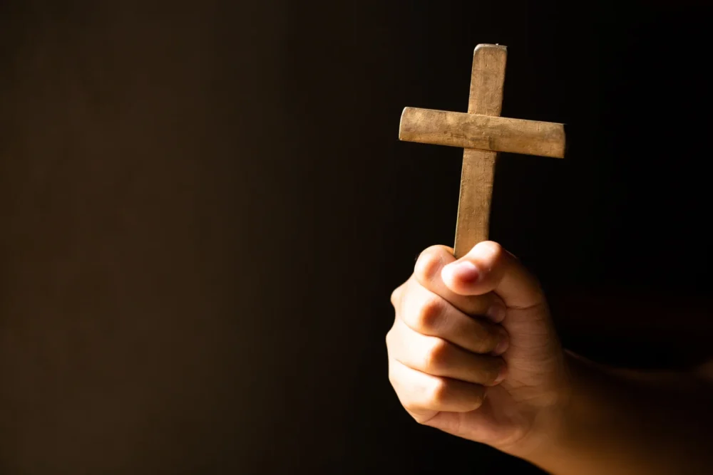 Hands holding cross while praying
